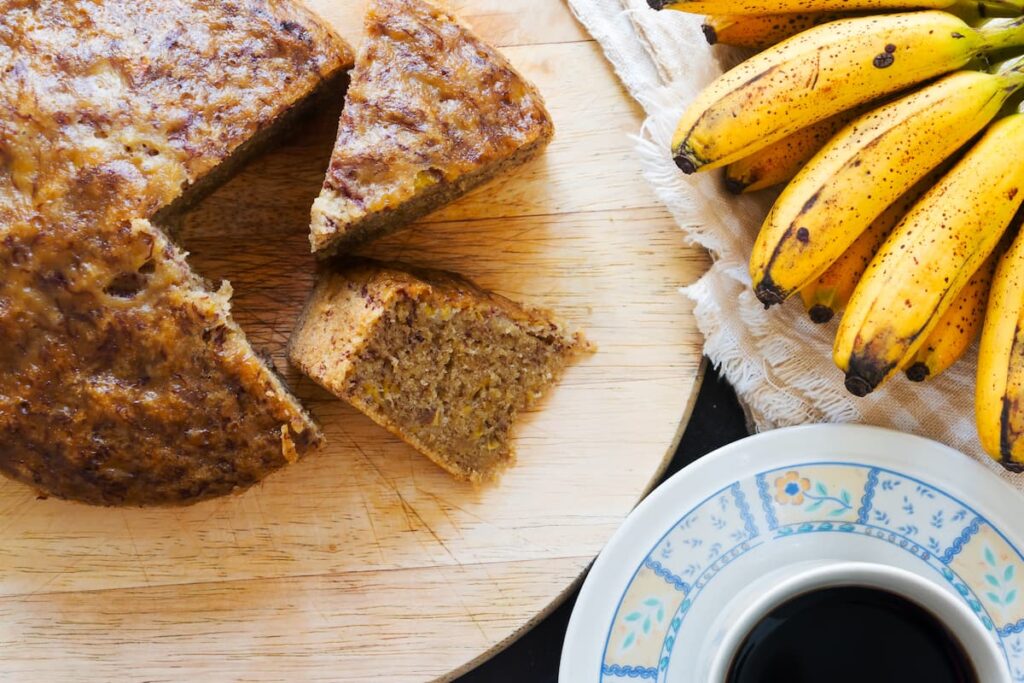 Imagem mostra pedaços de bolo de banana acompanhado de uma bela xícara de café.