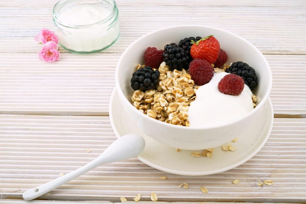 Imagem mostra iogurte natural com frutas vermelhas.
