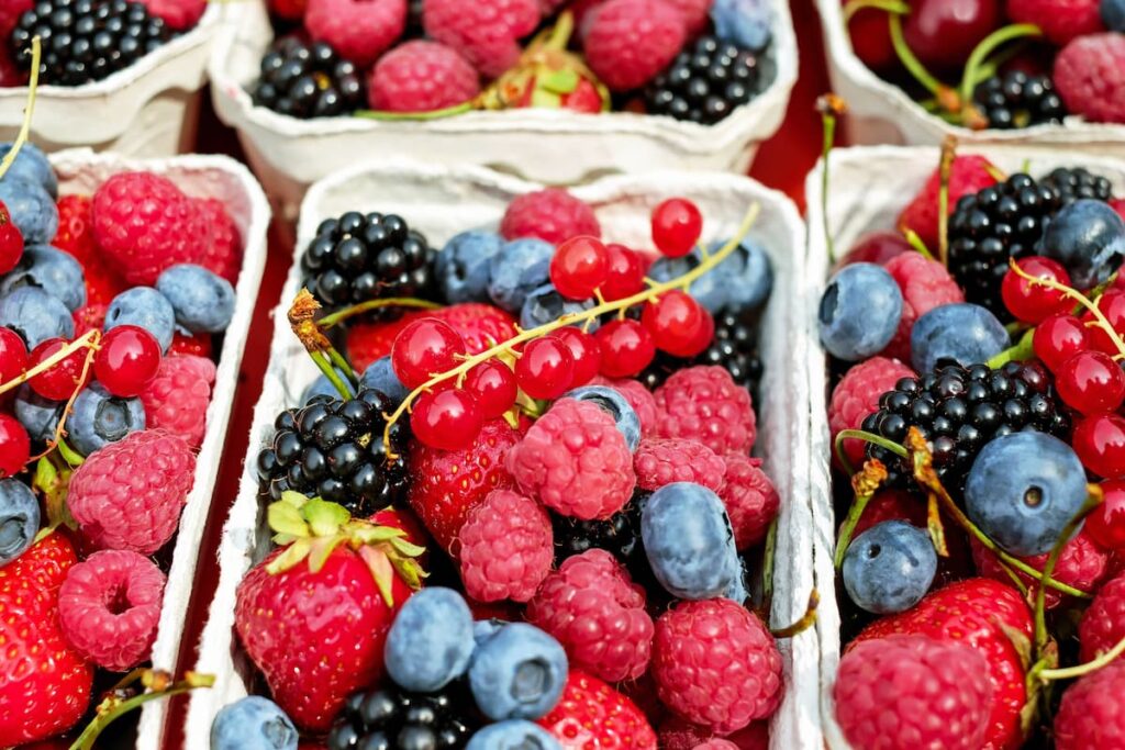 Imagem mostra bandejas de frutas vermelhas diversas.