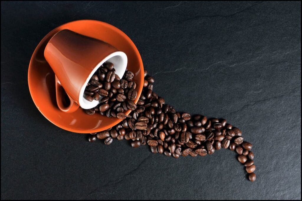 Imagem mostra xócara com grãos de café torrado.